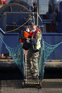 A person is carried ashore at Dover Harbour by a crew member from HMC Valiant after a group of migrants were picked up from the English Channel by the UK Border Force.