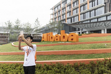 An employee takes a selfie in a garden outside at the Alibaba Group Holding Ltd. headquarters.