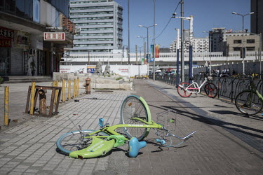 A shared bicycle lies broken on a street. While cheap, convenient, and theoretically environmentally friendly, the craze and commercialisation of shared bikes initially created massive waste.