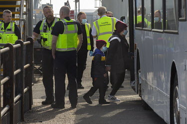 Immigration officers in Dover Harbour where a group of migrants enter a bus after coming ashore from HMC Valiant after the UK Border Force picked them up from the English Channel.