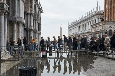 Tourists enter the Basilico San Marco, walking over flood water on elevated running boards. The famous square is at the lowest point in Venice and is consequently flooded during Acqua Alta or 'high wa...