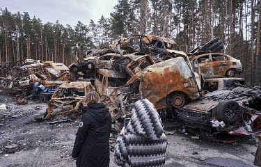 Two women looking at the burned out chassis of cars in a dump for vehicles destroyed by invading Russian forces which have been moved to a site near a cemetery on the outskirts of Irpin.