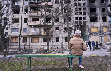 A young girl sits on the bench while she looks at a destroyed apartment block in the Obolon district. It was hit by a Russian shell in the early morning hours of 14 March 2022 killing two people and w...