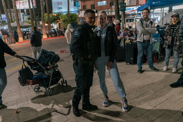 A Mexican police officer poses beside an Ukrainian refugee while she waits to enter in the United States near the San Ysidro border crossing.