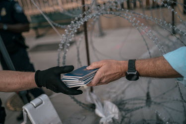 A volunteer gives a Customs and Border Protection (CBP) officer passports of Ukranians looking for asylum in the United States at the San Ysidro border crossing. The CBP has beenÂ�making exceptions o...