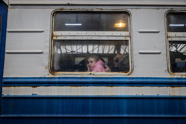 A young girl looks out a train carriage window while waiting to depart Lviv for Poland. She was one of thousands of women and children at the station waiting to board evacuation trains out of Ukraine...