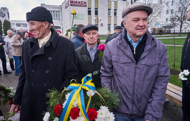 Chernobyl veterans carry a flower basket tied with a ribbon in the Ukrainian colours as they visit the Chernobyl Memorial which is dedicated to the firefighters and workers who went, ill-equipped, int...