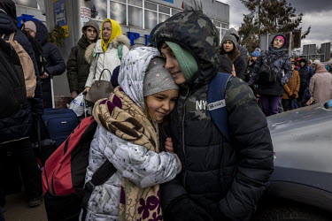 Daryna and her older brother Ilya, who fled their home in Kyiv, wait in line with their mother to cross into Poland. A crowd of several thousand or more, mainly women and children, queued up in the fr...
