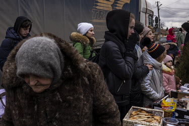 People wait to to receive free food distributed by a volunteer group near the border crossing. A crowd of several thousand or more, mainly women and children, queued up in the freezing cold at the She...