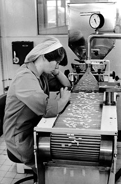 A worker, at the May and Baker factory, checking librium tablets on the production line.