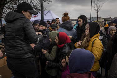Women and children, waiting for evacuation trains, queue to receive free food and water at a distribution point at Lviv train station.