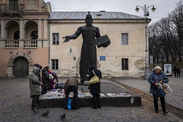 A woman sells books and trinkets in front of a statue of Ivan Fedorov.