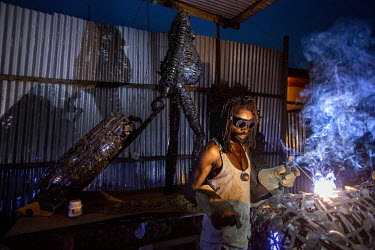 Artist, Freddy Tsimba welding pieces for a sculpture in his workshop. He says he finds his inspiration in the suffering experienced by many communities in his country. An advocate for disarmament, muc...