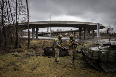 Ukrainian Military Intelligence soldiers inspect the remnants of a Russian tank on the side of the main highway leading west out of Kyiv that was destroyed by what the soldiers said was an American-ma...