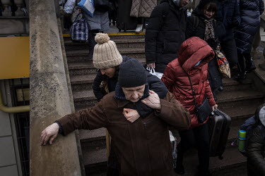 A woman and man help each other negotiate a flight of stairs as a train full of passengers crowd into Lviv train station after arriving from Kiev (Kyiv).