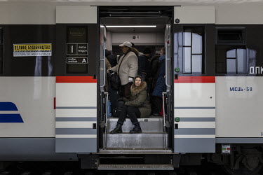 A woman sits in the doorway of a packed carriage on a train bound for Poland from Lviv station.