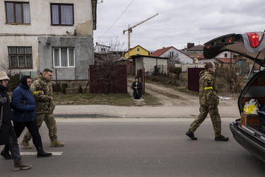A local resident kneels in front of her house as the funeral procession for Senior Sergent Yevhen Verveyko of the Ukranian National Army, who was killed fighting against Russian forces, passes through...