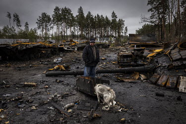 A man and his dog examine the burnt out remnants of as many as nine Russian tanks and armoured fighting vehicles litter a forested road leading out of the town of Dmytrivka. Ukrainian soldiers said th...