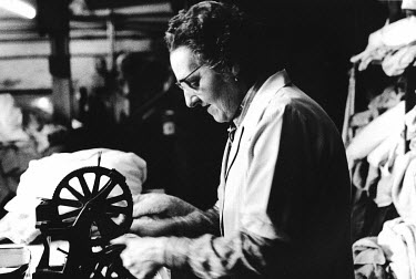 A worker making buttonholes at West London Pages Laundry.