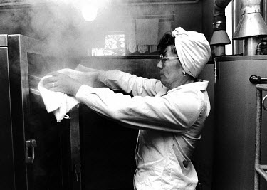 A school cook removes food from a steam oven.