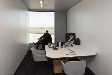 An employee making a phone call while looking out over the tarmac of Brussels airport at the headquarters of KPMG.