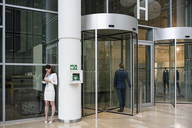 A woman looking at her smartphone in the entrance hall of the World Trade Center in Zuidas.