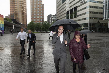People walking in the rain in the Gustav Mahlerplein financial district in Amsterdam South.
