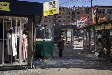 A woman talks on her mobile phone while standing amidst damaged shops, at the site of a Russian missile strike near the Lukyanivska metro.