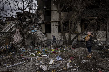 Tanya Hachnikova (36) and Oksana Dikan (43) wait outside a destroyed apartment block while their husbands attempted to find a way into the basement where Tanya's parents-in-law died, along with more t...