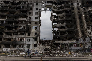 A man rides a bicycle past an apartment block that has been badly damaged during the Russian invasion. According to the town's acting mayor, as many as 200 people are missing, presumed dead, still lyi...
