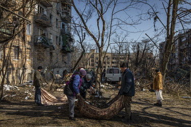 Local residents and municipal workers join together to clean up the courtyard area of an apartment complex the day after the area was hit by a Russian strike.