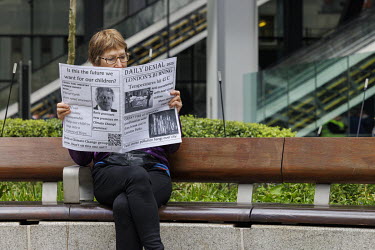 A woman reads an Extinction Rebellion handout during a protest at the Lloyds of London insurance building in the City of London.