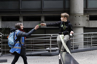 A woman takes an Extinction Rebellion sticker handed out by a boy during a protest at the Lloyds of London insurance building in the City of London.