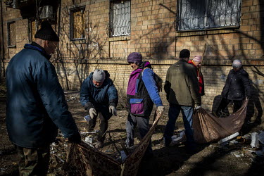 Local residents and municipal workers join together to clean up the courtyard area of an apartment complex the day after the area was hit by a Russian strike.