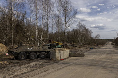 An abandoned Russian armoured vehicle, bearing the letter 'V', at a checkpoint on a road in the Exclusion Zone leading to the Chernobyl power plant.