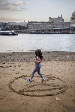 An Extinction rebellion logo drawn in the sand beside the River Thames outside the Tate Modern.
