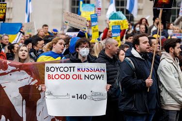 A man holds a sign that reads: 'Boycott Russian Blood Oil Now!' during a solidarity protest in Whitehall against the Russian invasion of Ukraine. The protest brought together Ukrainians, Russians, Uyg...