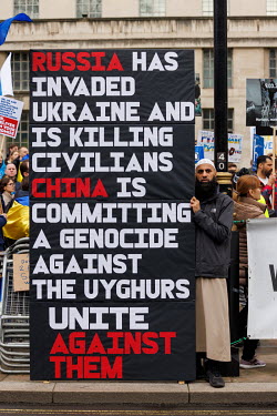 A Muslim protestor holds a huge sign that reads: 'Russia has invaded Ukraine and is killing civilians, China is committing a genocide against the Uyghurs, Unite against them' during a solidarity prote...
