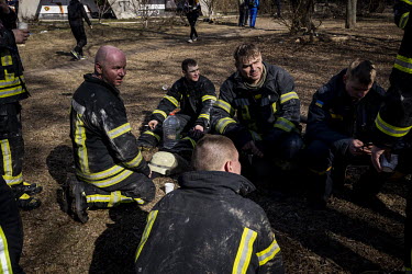 Exhausted fire fighters rest after battling a fire and rescuing people from an apartment building in western Kyiv that was hit by Russian shelling and caught on fire.