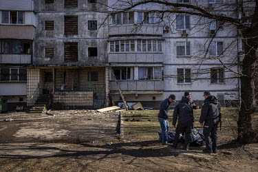 Police officers help a man identify the bodies of his family members, who died after their building in western Kyiv was hit by Russian shelling and caught on fire.