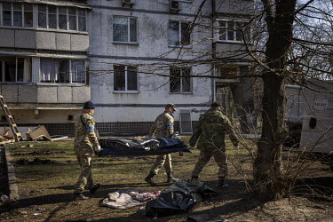 Soldiers carry away the bodies of two people who died after their building in western Kyiv was hit by Russian shelling and caught on fire.