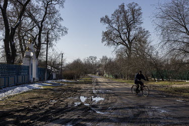 A man rides a bicycle along a muddy road in the village of Nova Basan. The area was liberated from Russian forces on the 31 March 2022.