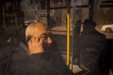 An elderly man sits on a bus making a call on his mobile phone. He was one of a steady stream of civilians who arrived in minivans and ambulances, some injured, at an aid station in north west Kyiv, h...