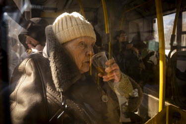 An elderly woman sits on a bus drinking tea. She was one of a steady stream of civilians who arrived in minivans and ambulances, some injured, at an aid station in north west Kyiv, having being evacua...