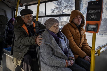 An elderly man comforts a woman as they sit on a bus waiting to be transported elsewhere. They were some of a steady stream of civilians who arrived in minivans and ambulances, some injured, at an aid...
