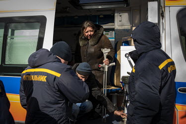 Emergency services staff help a disabled man from an ambulance as a steady stream of civilians, who arrived in minivans and ambulances, some injured, at an aid station in north west Kyiv, having being...