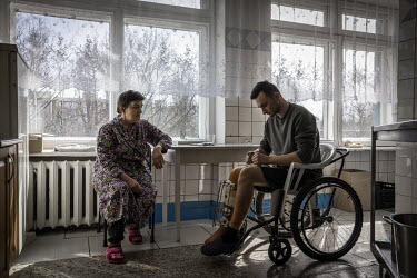 Oleksii (20) talks with the wife of another patient at the hospital where he is recovering having been shot in the leg while on duty as a volunteer fighter in Kyiv.