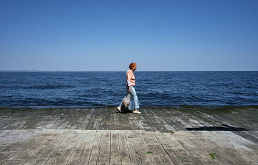 A woman walks on an empty Langeron Beach promenade, normally bustling with people.