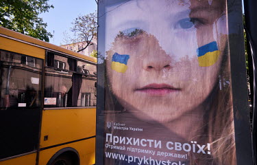 A poster at the bus stop featuring a girl with the Ukrainian flag painted on her cheeks, reads: 'Shelters of their own, get state support.'