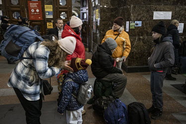 A family wait for their train to Poland at Kyiv's central station after recently fleeing their home in the Sumy region.